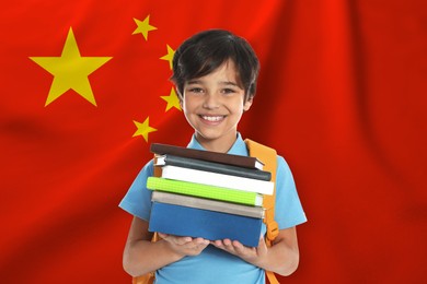 Image of Little boy with books and backpack against flag of China. Language school