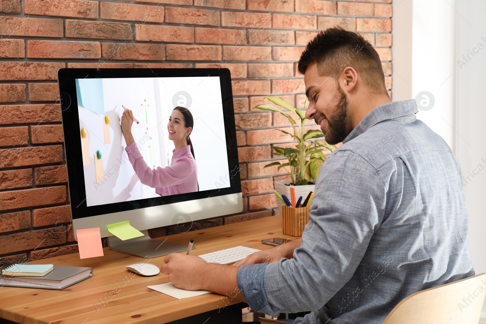 Image of E-learning concept. Student having online video chat with teacher via computer at desk