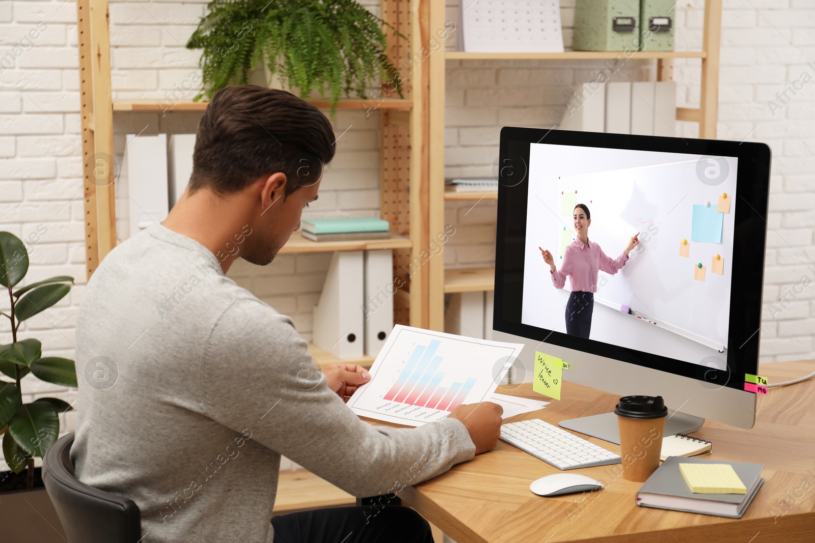 Image of E-learning concept. Student having online video chat with teacher via computer at desk