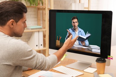 Image of E-learning concept. Student having online video chat with teacher via computer at desk