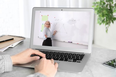 Image of E-learning concept. Student having online video chat with teacher via laptop at desk, closeup