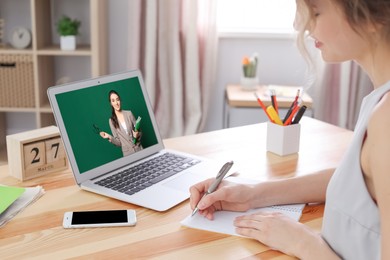 Image of E-learning concept. Student having online video chat with teacher via laptop at desk, closeup