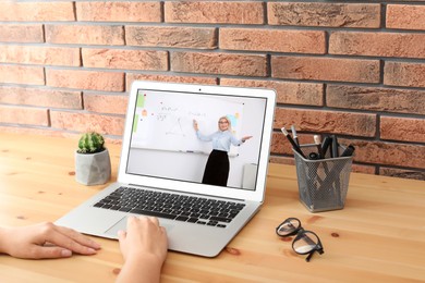 Image of E-learning concept. Student having online video chat with teacher via laptop at desk, closeup