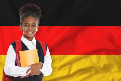 Image of Little girl with backpack and notebooks against flag of Germany. Language school