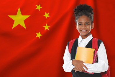 Image of Little girl with backpack and notebooks against flag of China. Language school