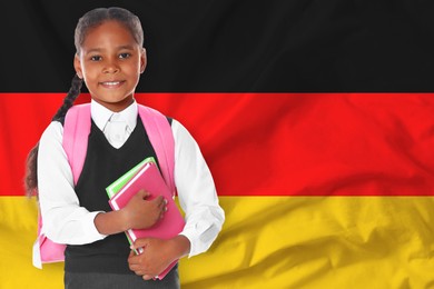 Image of Little girl with backpack and notebooks against flag of Germany. Language school