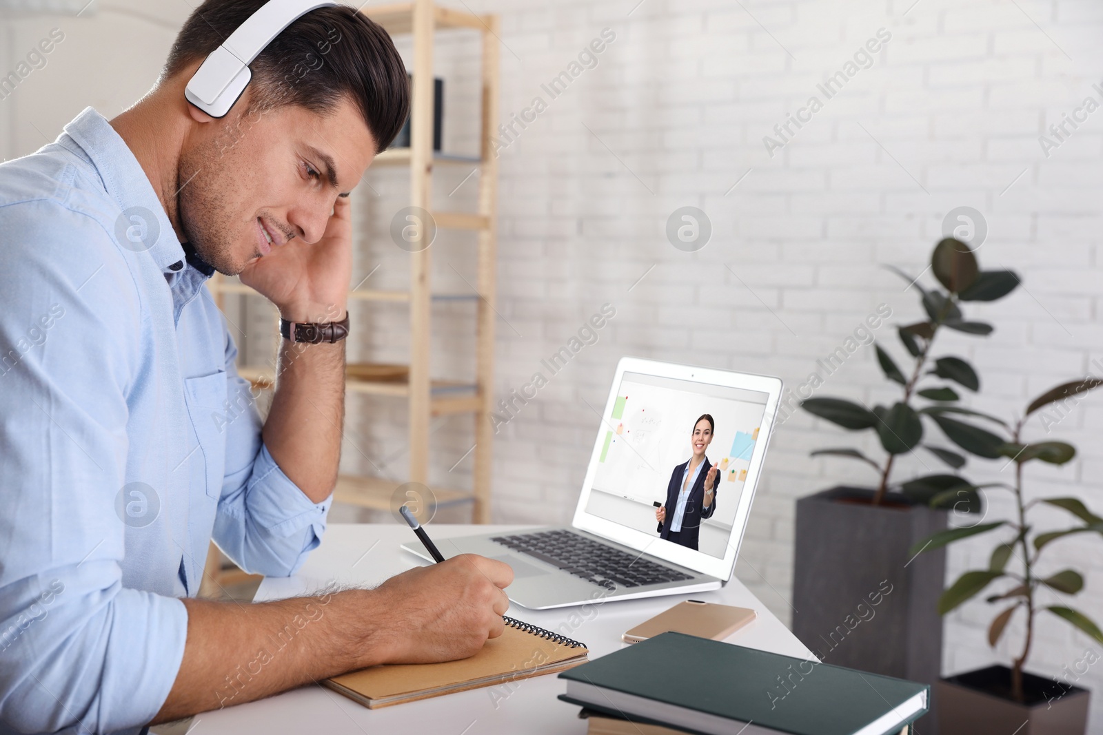 Image of E-learning concept. Student having online video chat with teacher via laptop at desk