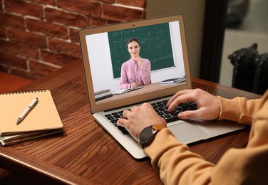 Image of E-learning concept. Student having online video chat with teacher via laptop at desk, closeup