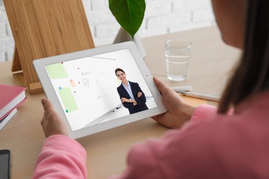 Image of E-learning concept. Student having online video chat with teacher via tablet computer at desk, closeup