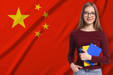 Image of Student with notebooks against flag of China. Language school