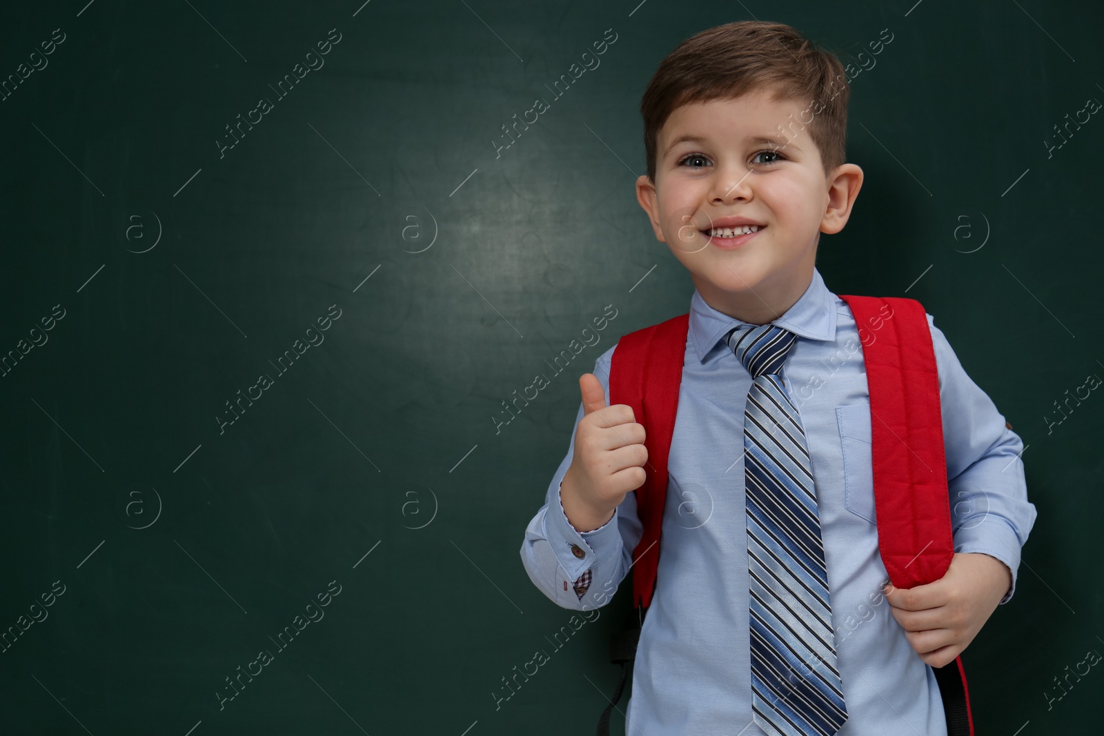 Cute little child near chalkboard, space for text. First time at school Photo of Cute little child near chalkboard, space for text. First time at school