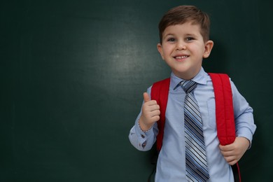 Photo of Cute little child near chalkboard, space for text. First time at school