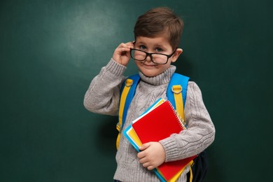Photo of Cute little child wearing glasses near chalkboard. First time at school