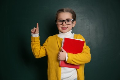 Photo of Cute little child wearing glasses near chalkboard. First time at school