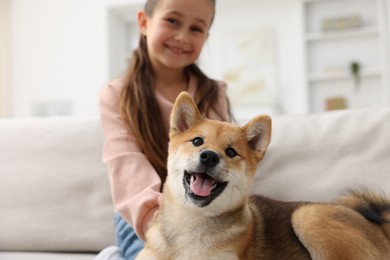 Photo of Cute dog and smiling little girl on sofa at home