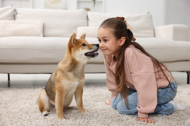 Photo of Cute little girl with her dog on floor at home. Child and pet
