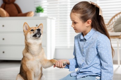 Photo of Cute little girl with her dog on floor at home. Child and pet