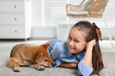 Photo of Smiling little girl with her dog on floor at home. Child and pet