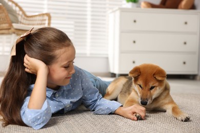 Photo of Cute little girl with her dog on floor at home. Child and pet