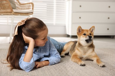 Photo of Cute little girl with her dog on floor at home. Child and pet