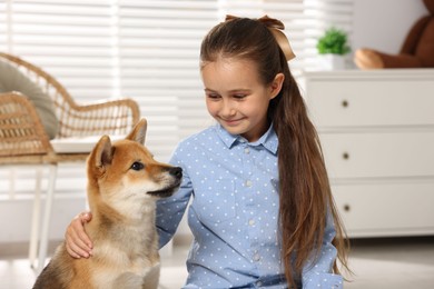 Photo of Cute little girl with her dog on floor at home. Child and pet
