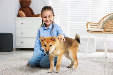 Photo of Smiling little girl with her dog on floor at home. Child and pet