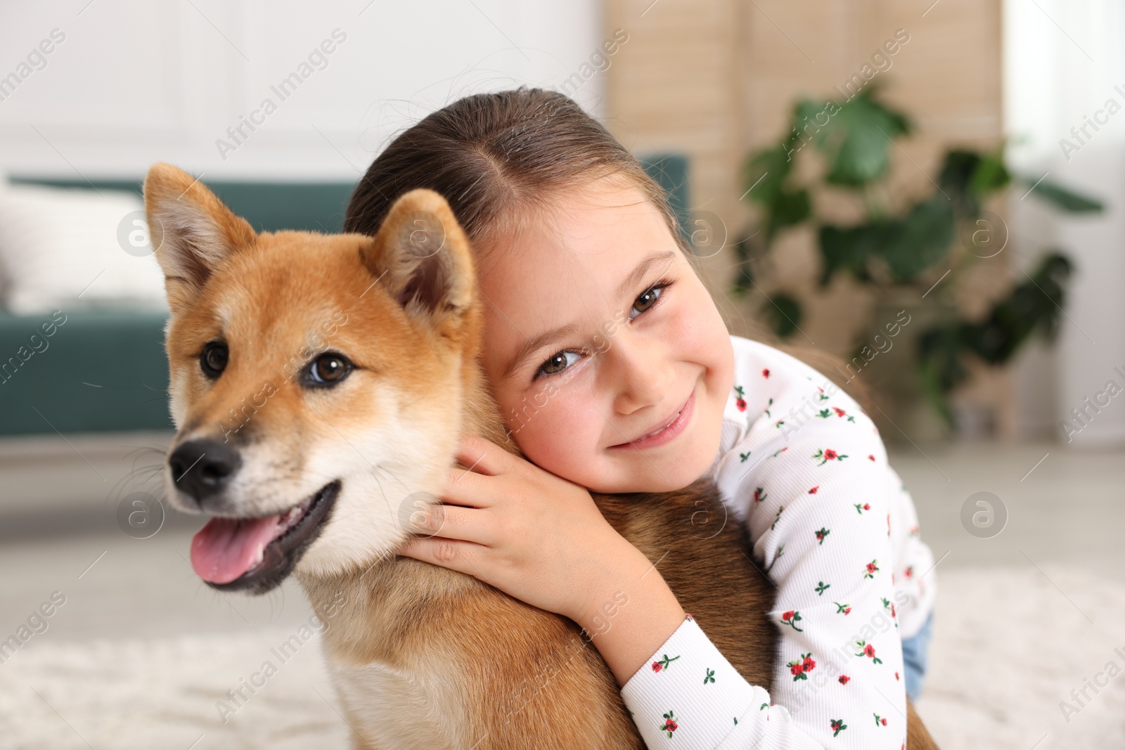 Portrait of cute little girl with her dog on floor at home. Child and pet Photo of Portrait of cute little girl with her dog on floor at home. Child and pet