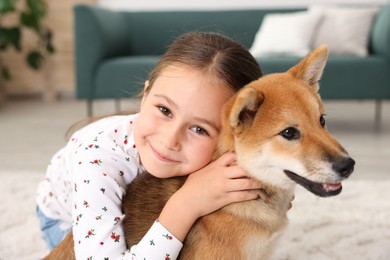 Photo of Portrait of cute little girl with her dog on floor at home. Child and pet