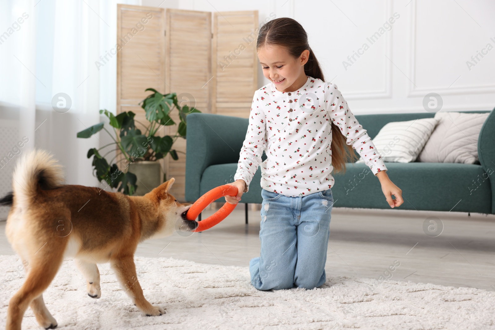 Smiling little girl playing with her dog on floor at home. Child and pet Photo of Smiling little girl playing with her dog on floor at home. Child and pet