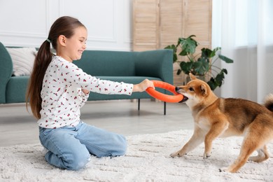 Photo of Smiling little girl playing with her dog on floor at home. Child and pet