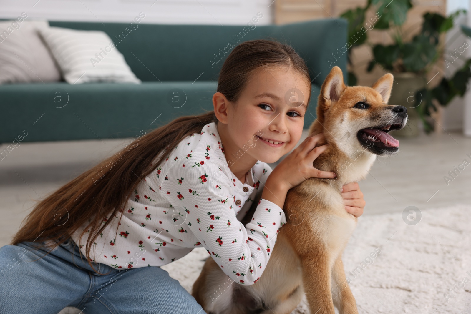 Portrait of smiling little girl with her dog on floor at home. Child and pet Photo of Portrait of smiling little girl with her dog on floor at home. Child and pet