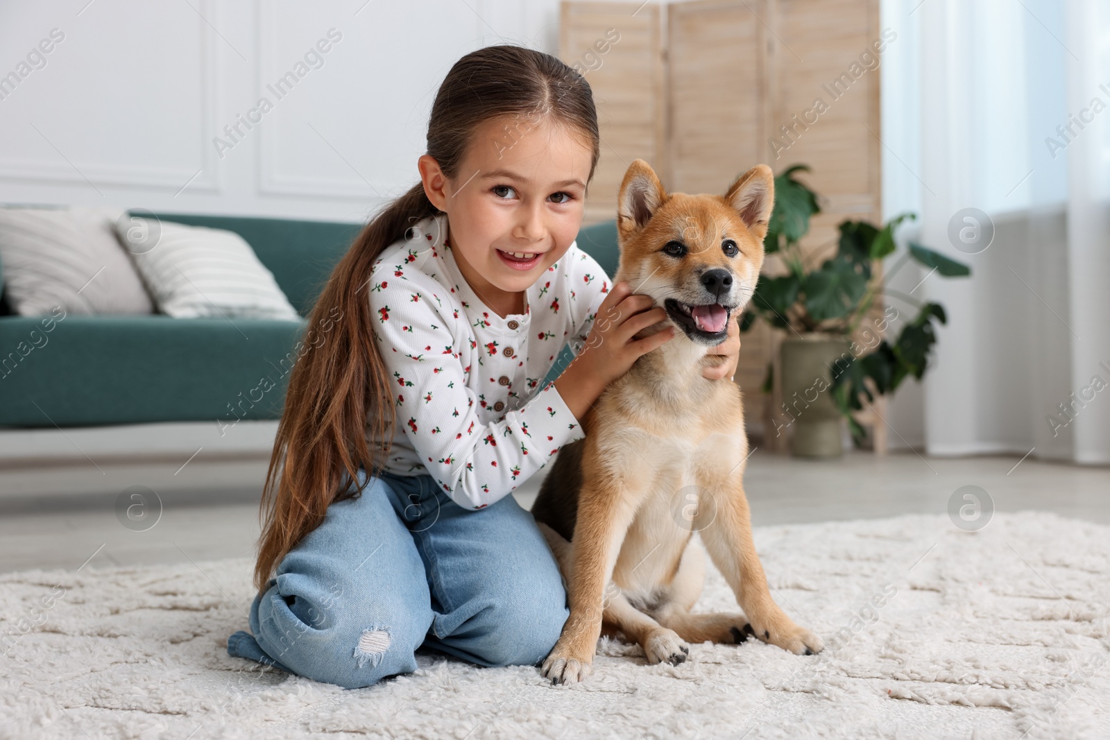 Smiling little girl with her dog on floor at home. Child and pet Photo of Smiling little girl with her dog on floor at home. Child and pet
