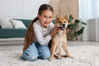 Photo of Smiling little girl with her dog on floor at home. Child and pet