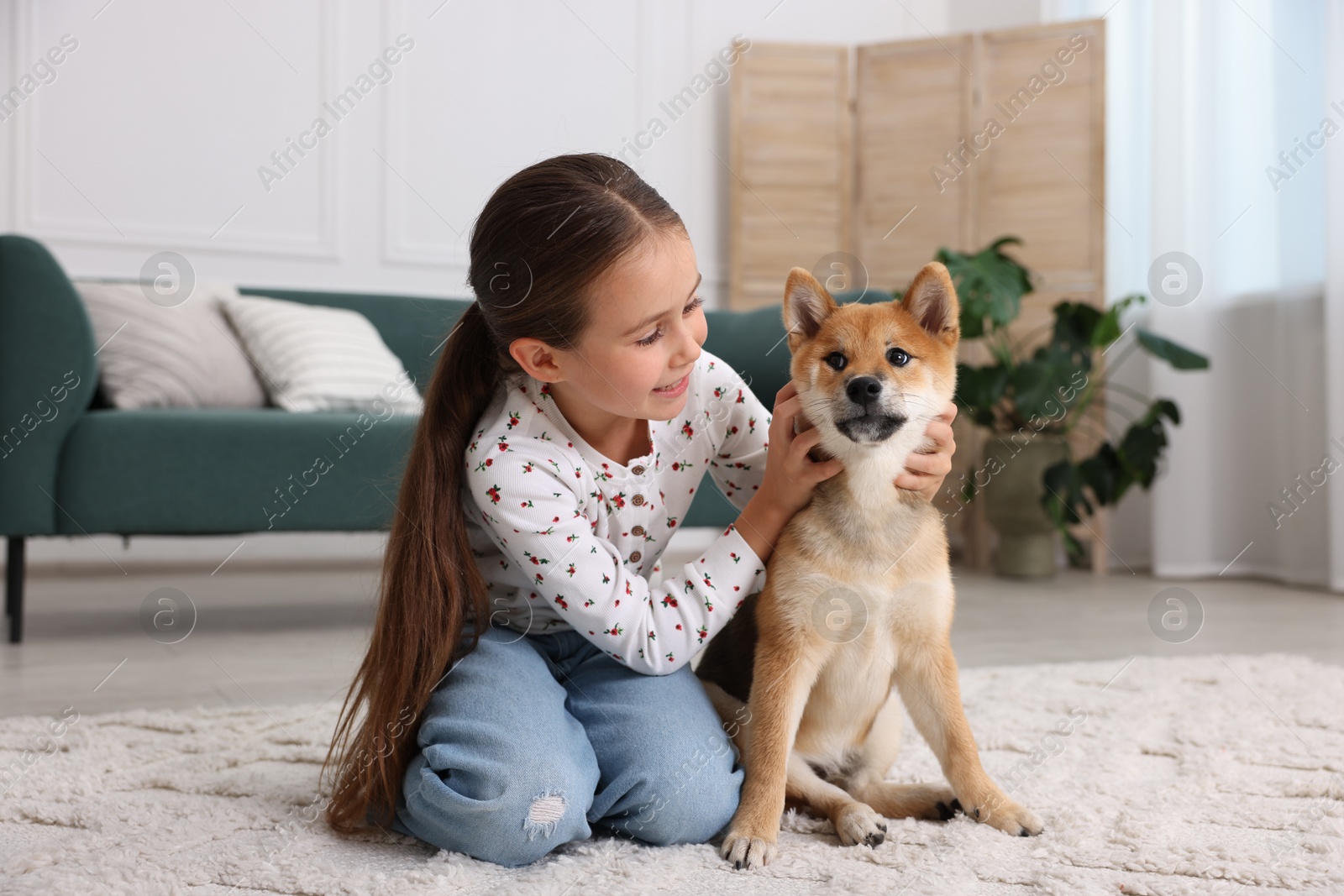 Smiling little girl with her dog on floor at home. Child and pet Photo of Smiling little girl with her dog on floor at home. Child and pet