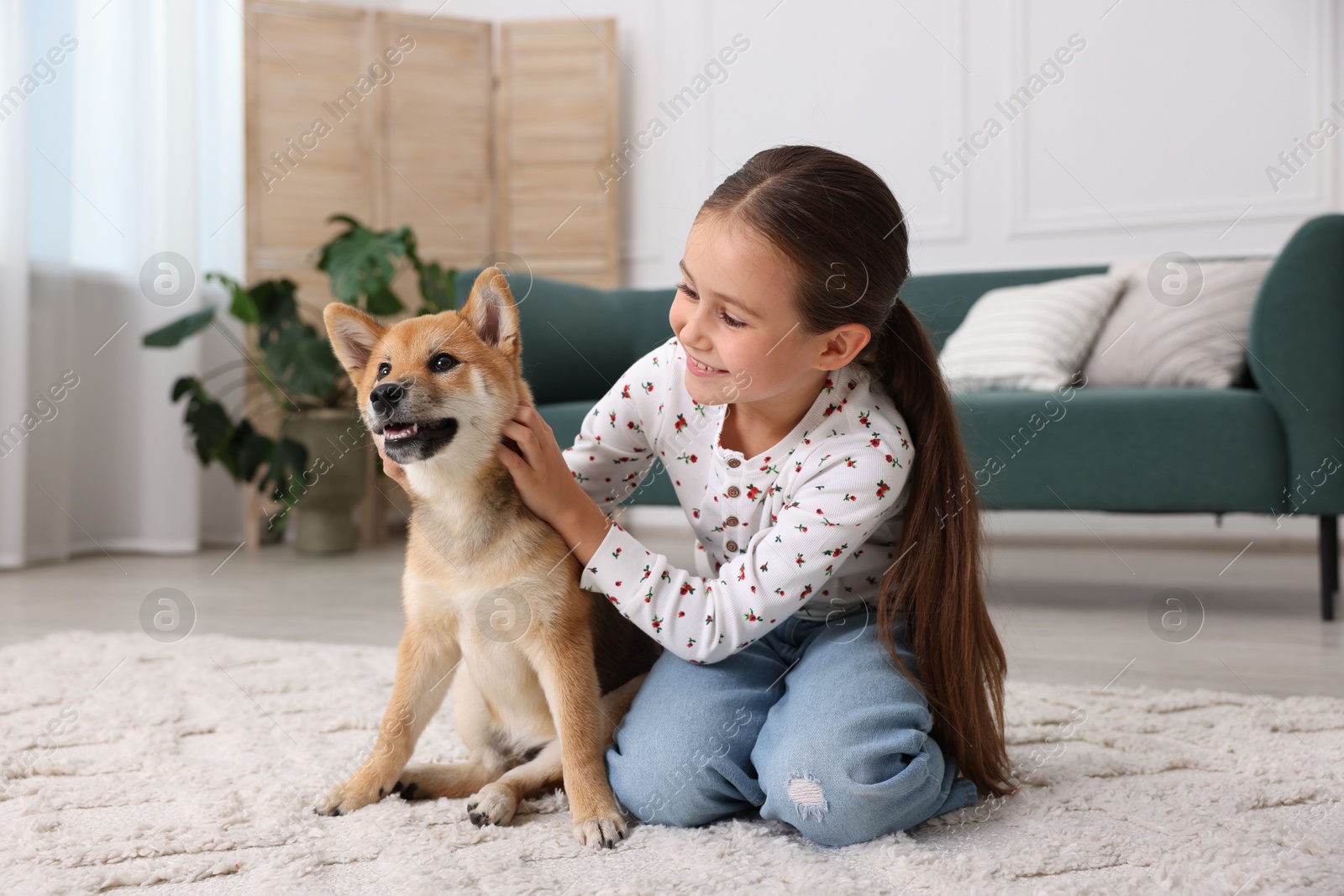 Smiling little girl with her dog on floor at home. Child and pet Photo of Smiling little girl with her dog on floor at home. Child and pet