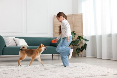 Photo of Cute little girl playing with her dog on floor at home. Child and pet