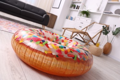 Photo of Bright inflatable donut shaped ring on wooden floor indoors, closeup. Dreaming about vacation at sea