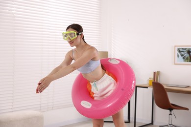 Photo of Woman in diving mask with inflatable ring having fun at home. Dreaming about vacation at sea