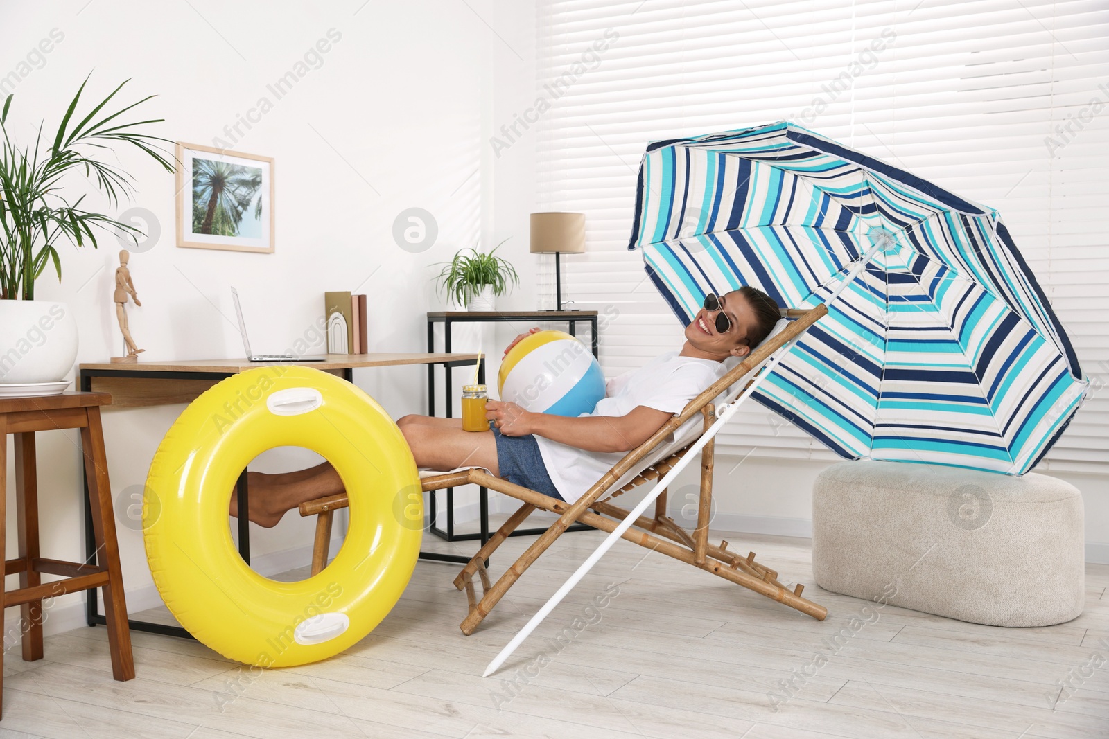 Happy man in sunglasses with mason jar of juice and beach ball having fun on sunbed at home. Dreaming about vacation at sea Photo of Happy man in sunglasses with mason jar of juice and beach ball having fun on sunbed at home. Dreaming about vacation at sea