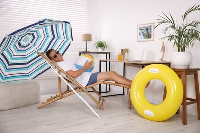 Photo of Happy man in sunglasses with beach ball having fun on sunbed at home. Dreaming about vacation at sea