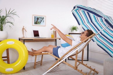 Photo of Happy man in sunglasses with beach ball having fun on sunbed at home. Dreaming about vacation at sea