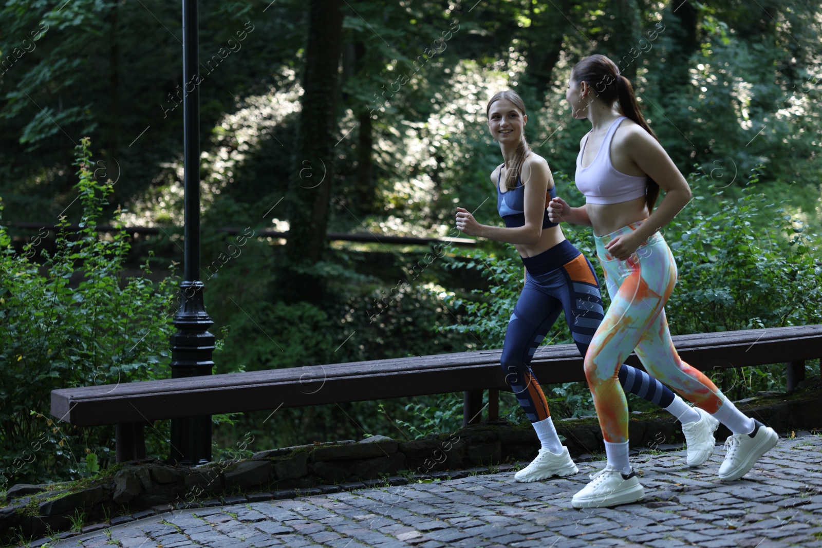 Photo of Young woman running with professional personal trainer outdoors. Space for text