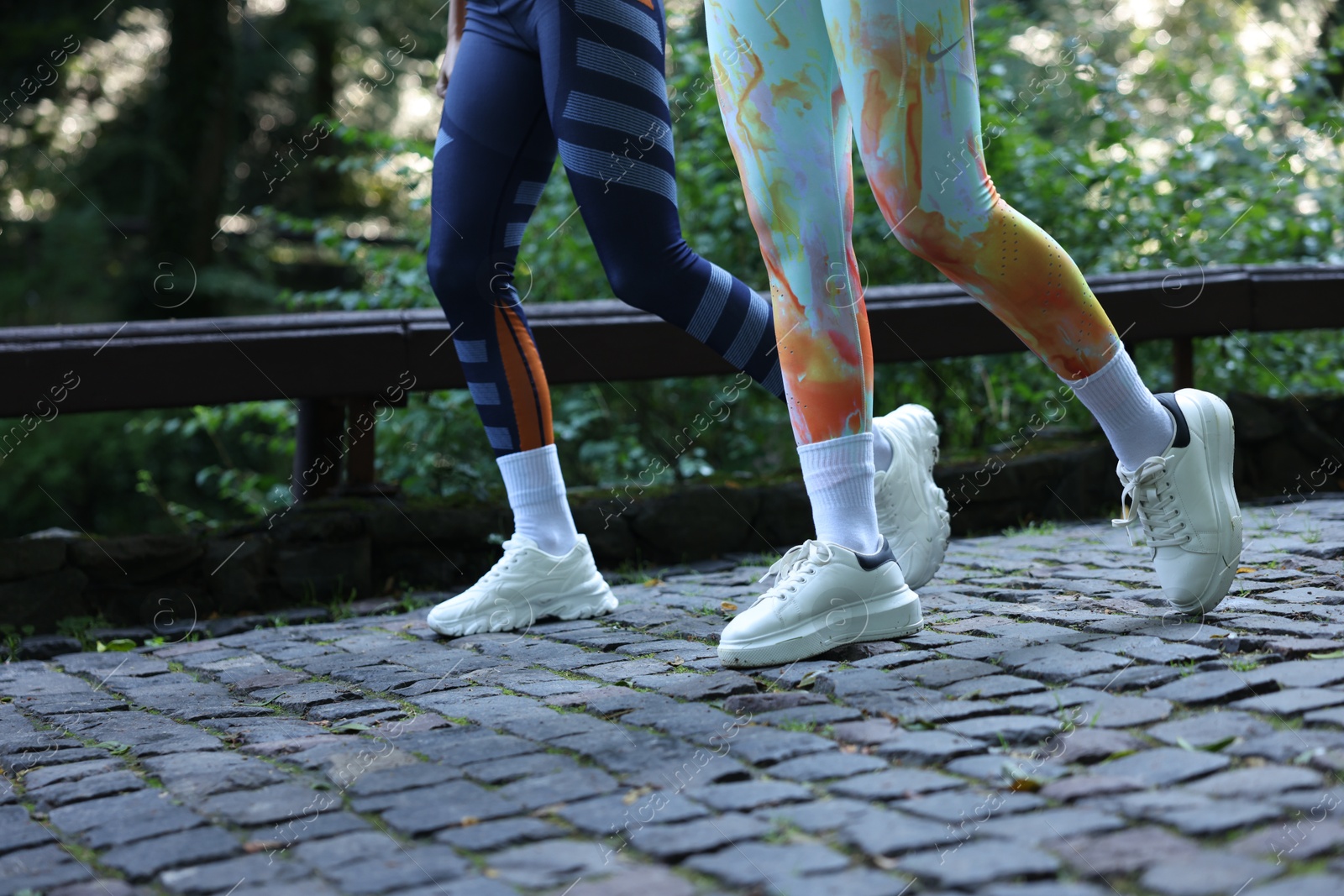 Photo of Young woman running with professional personal trainer outdoors, closeup