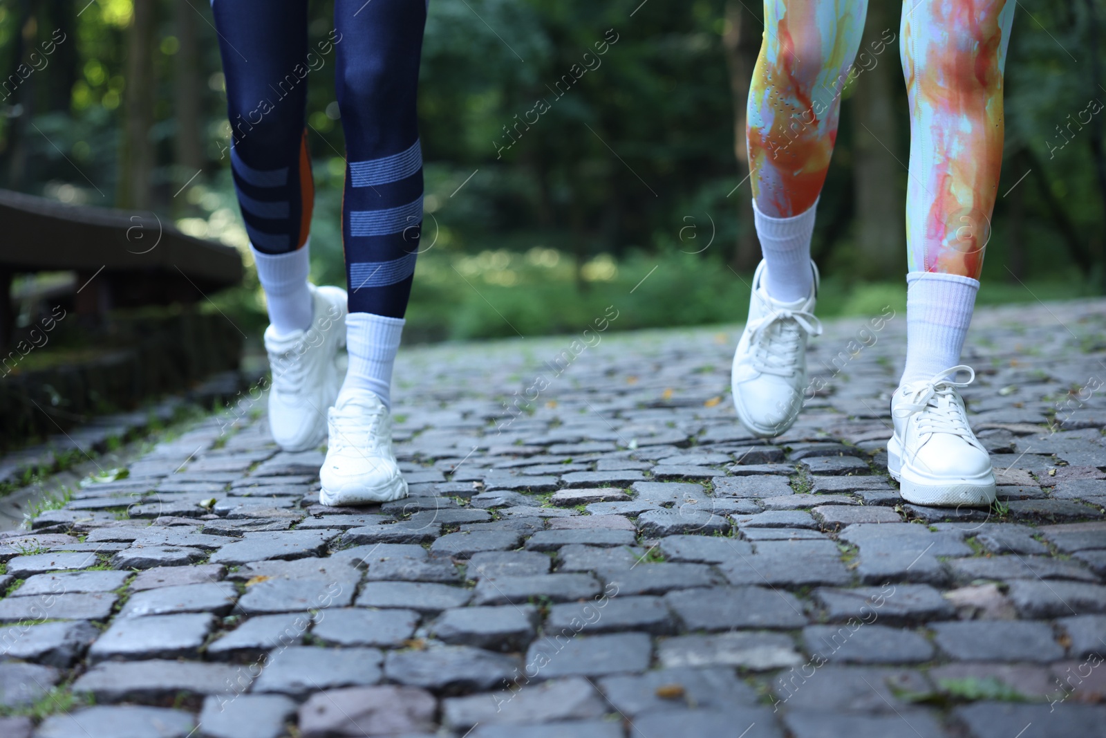 Photo of Young woman running with professional personal trainer outdoors, closeup