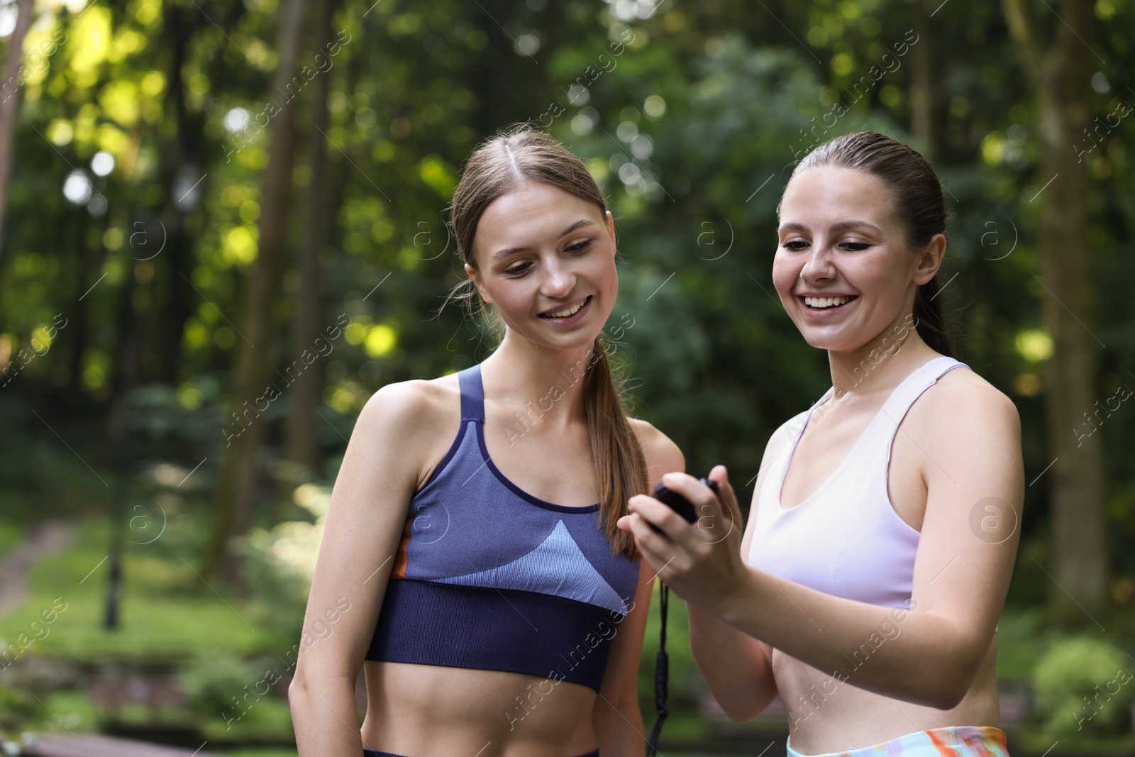 Photo of Happy young woman with professional personal trainer outdoors