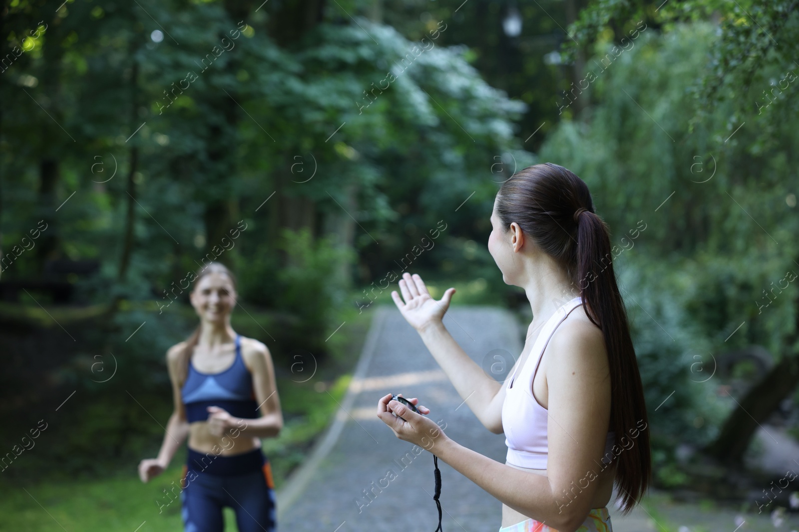 Photo of Young woman running with professional personal trainer outdoors, selective focus