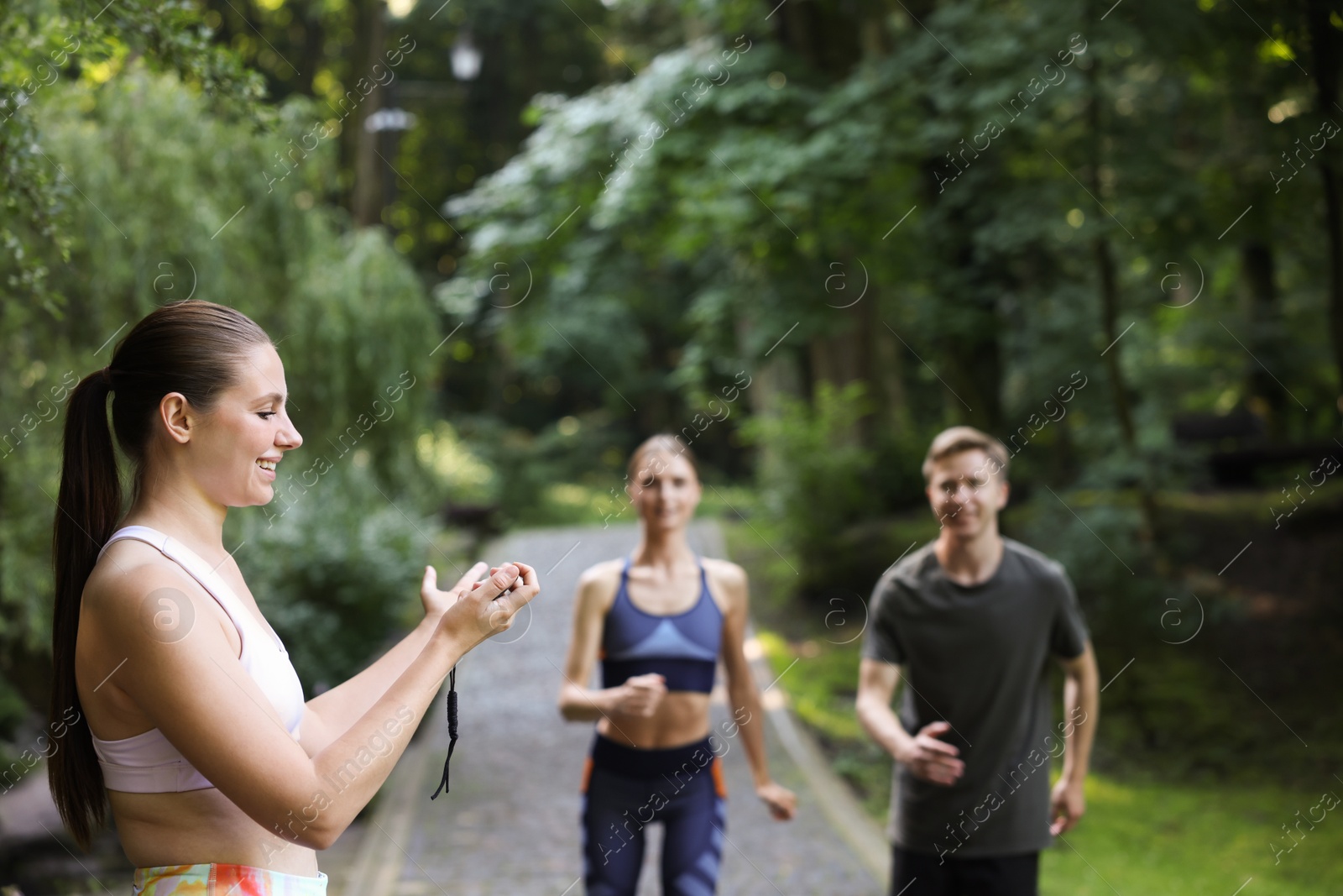 Photo of Young man and woman exercising with professional personal trainer outdoors, selective focus