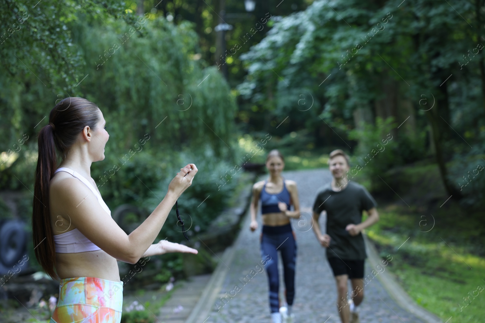 Photo of Young man and woman exercising with professional personal trainer outdoors, selective focus