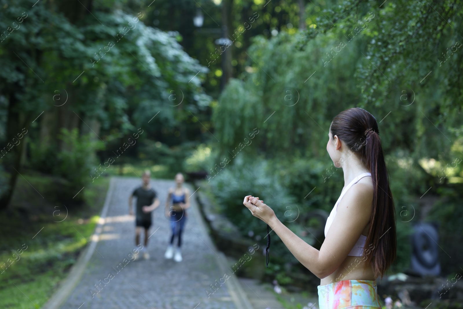 Photo of Young man and woman exercising with professional personal trainer outdoors, selective focus