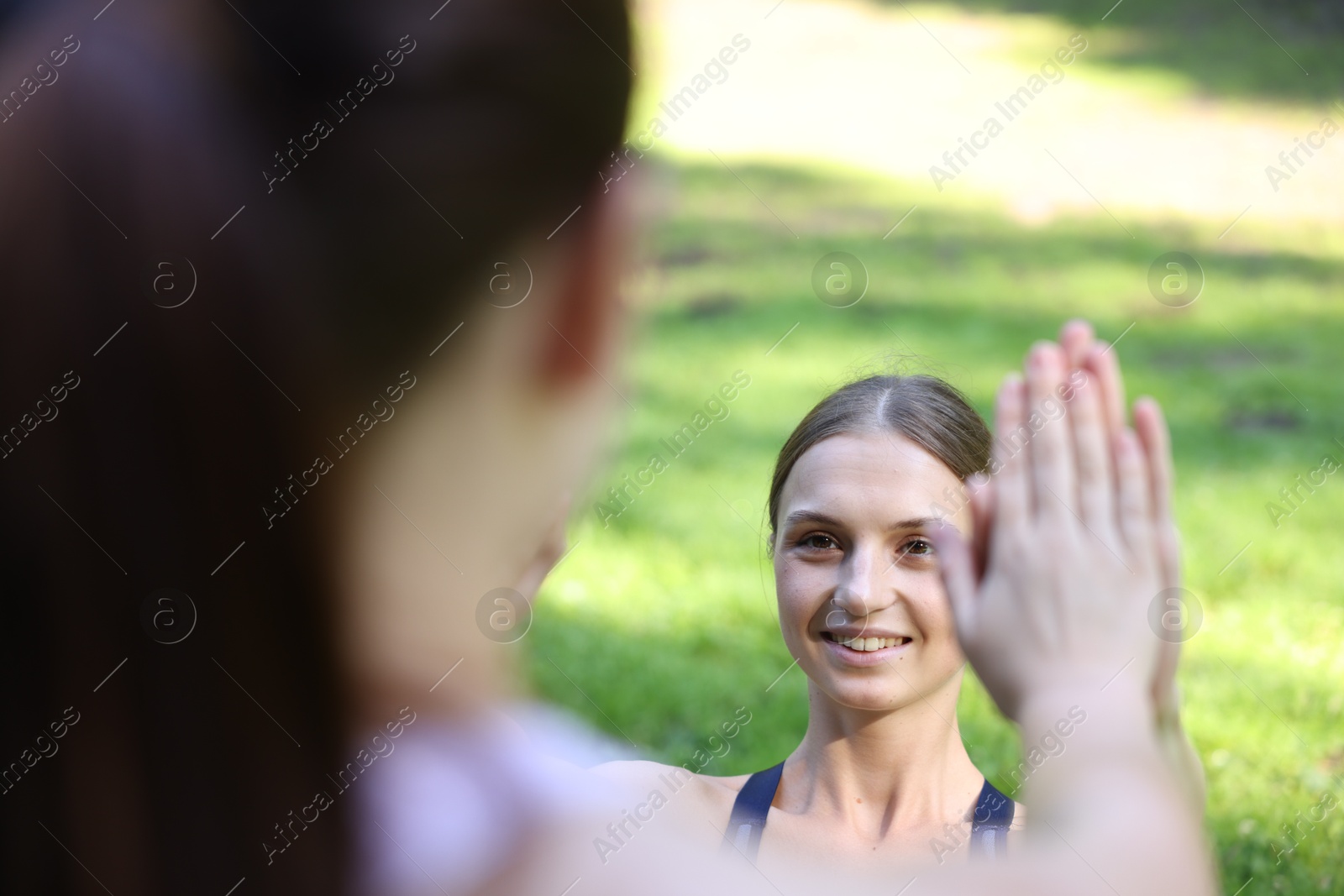 Photo of Young woman with professional personal trainer giving high five outdoors